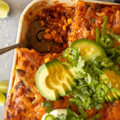 Close-up of melted cheese, avocado slices, and jalapeños on top of baked Mexican lasagna.