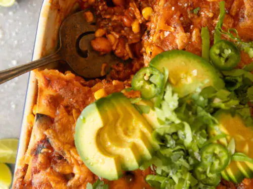 Close-up of melted cheese, avocado slices, and jalapeños on top of baked Mexican lasagna.