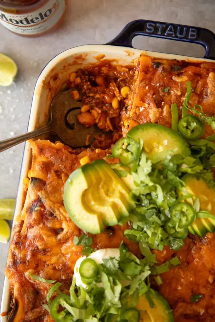 Close-up of melted cheese, avocado slices, and jalapeños on top of baked Mexican lasagna.