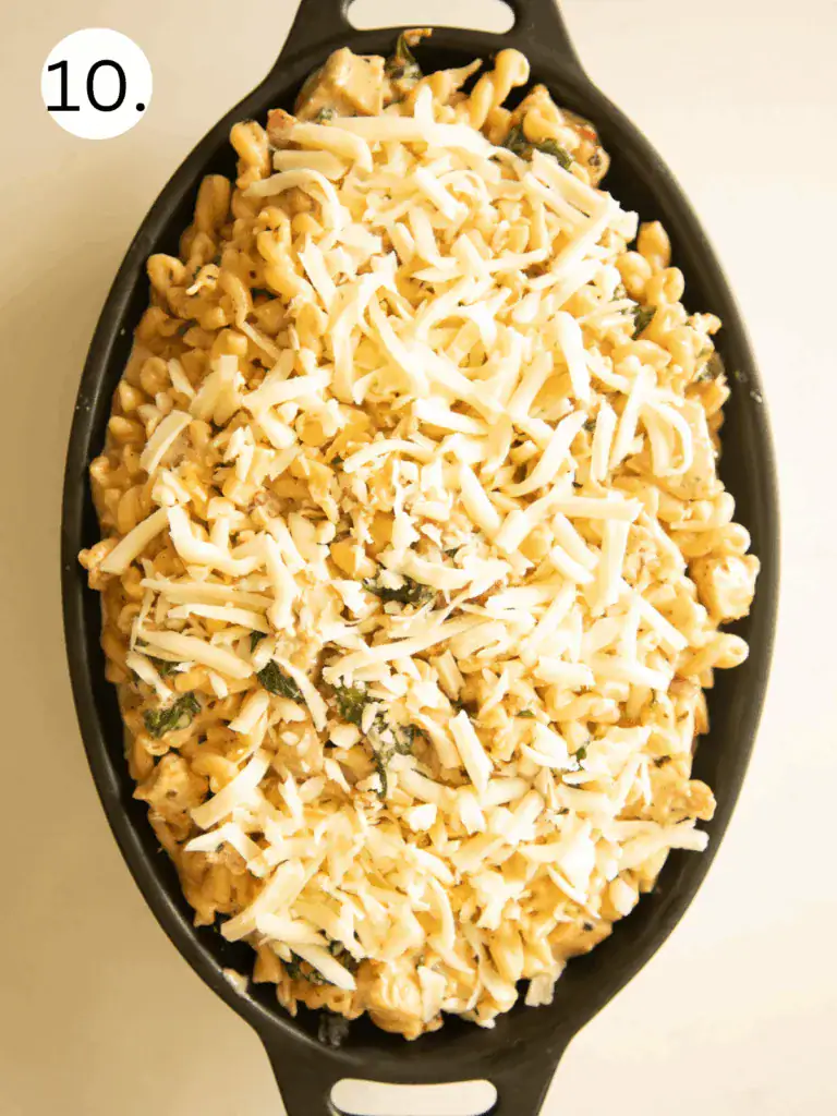 Pasta mixture in a baking dish topped with shredded mozzarella and parmesan cheese before baking.