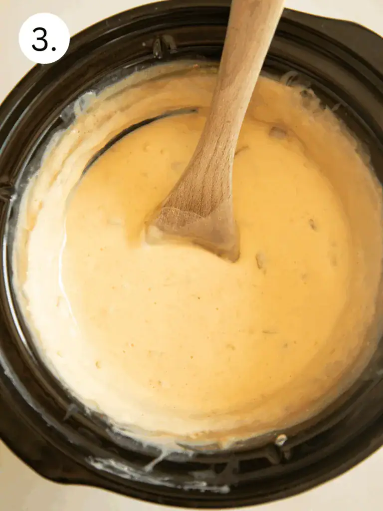 Creamy queso dip fully melted and stirred in a slow cooker.