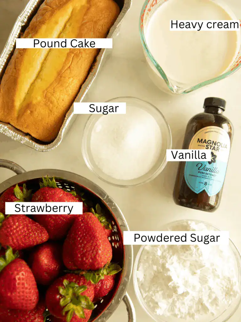 Top-down view of labeled ingredients including pound cake, strawberries, heavy cream, sugar, powdered sugar, and vanilla extract.