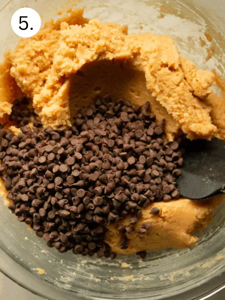 Mixing chocolate chips into the blended and stirred high-protein cookie dough made with cottage cheese and almond flour.