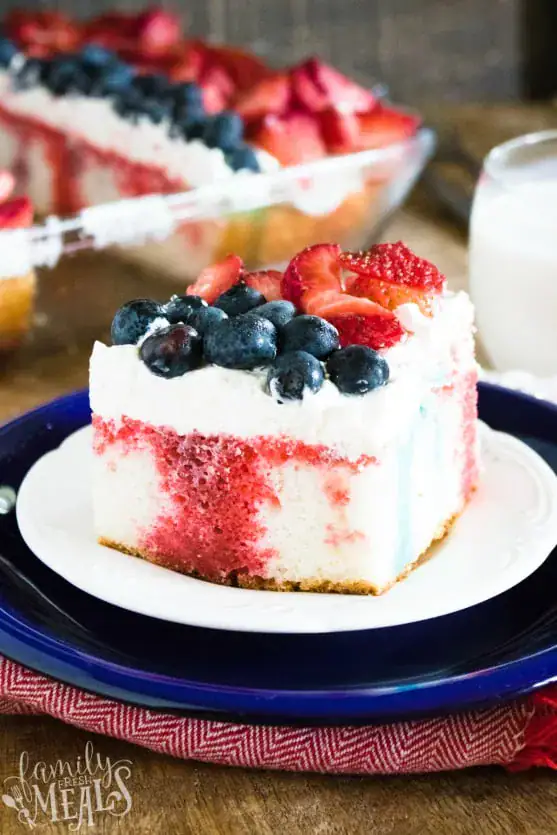 Light and airy poke cake topped with whipped cream and berries.