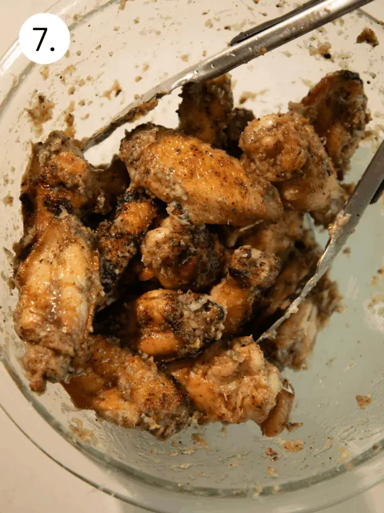 Grilled wings tossed with butter, black pepper, and grated Pecorino Romano in a glass bowl