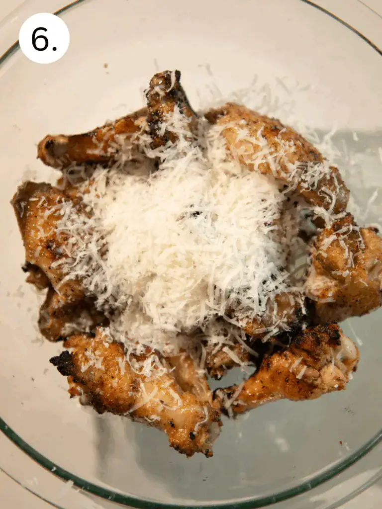 Hot grilled wings in bowl topped with shredded Pecorino Romano before tossing