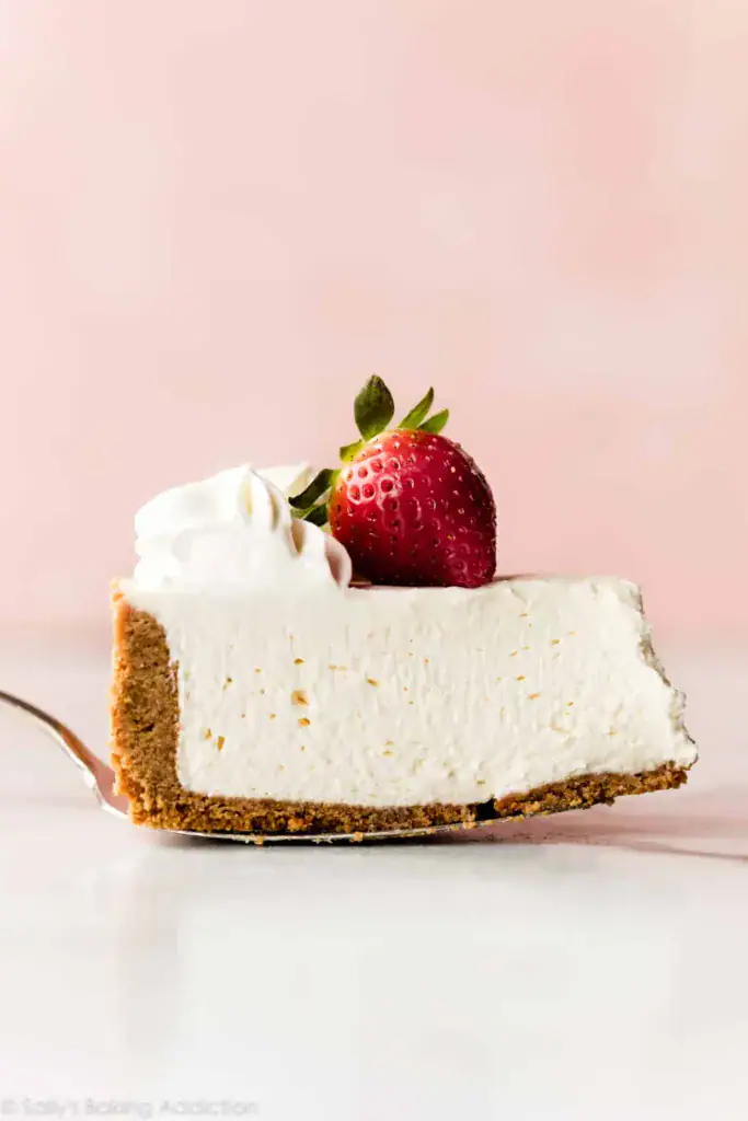 a slice of cheesecake with a strawberry in a pink background