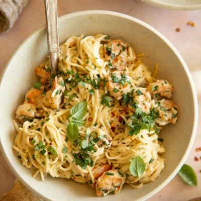Overhead shot of shrimp scampi pasta garnished with basil and served with crusty bread.