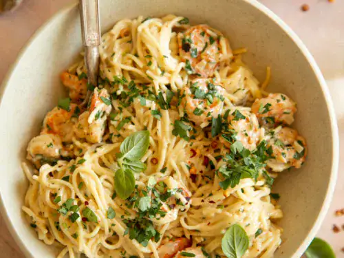 Overhead shot of shrimp scampi pasta garnished with basil and served with crusty bread.