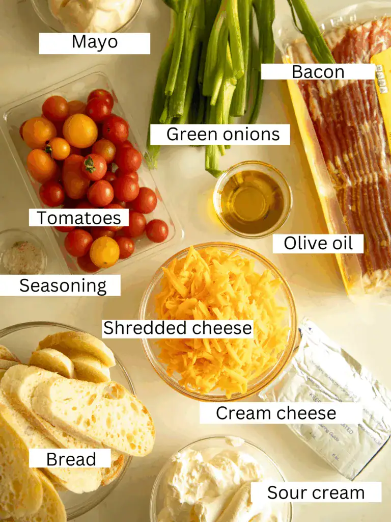 Overhead view of BLT dip ingredients including mayo, cream cheese, sour cream, tomatoes, bacon, green onions, and shredded cheese