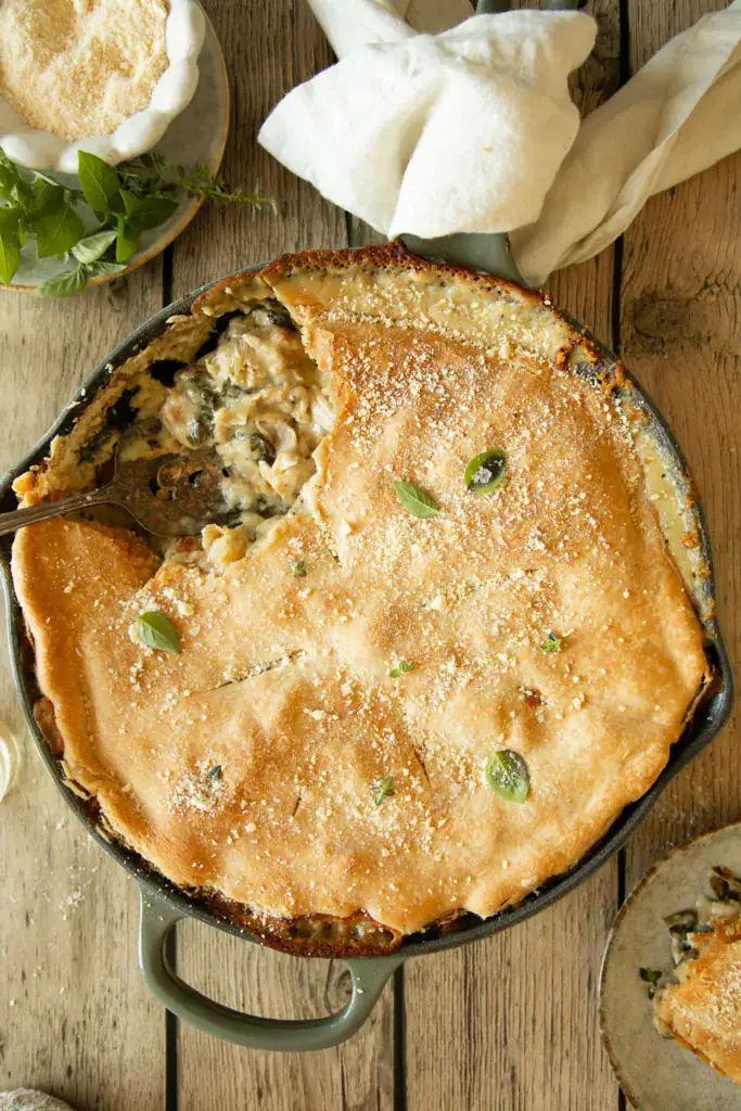 Overhead photo of pot pie with a slice removed, showing creamy filling with chicken and spinach under the flaky crust.