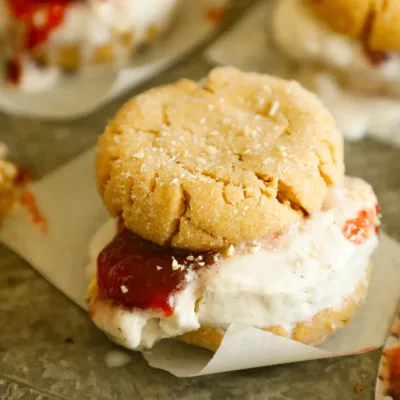 Close-up of a peanut butter and jelly ice cream sandwich with cracked cookie tops and chopped peanuts