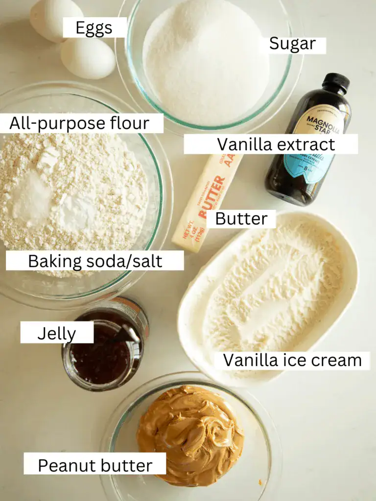 Overhead shot of ingredients for peanut butter and jelly ice cream sandwiches, including flour, sugar, butter, eggs, vanilla, peanut butter, jelly, and vanilla ice cream