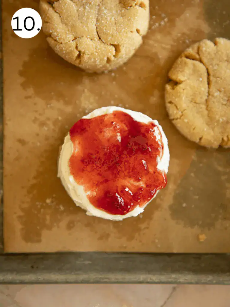 Step showing vanilla ice cream topped with strawberry jelly before being sandwiched between peanut butter cookies
