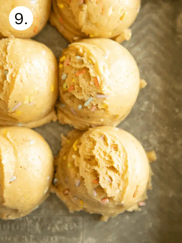 Scoops of brown butter funfetti cookie dough with sprinkles on a baking tray