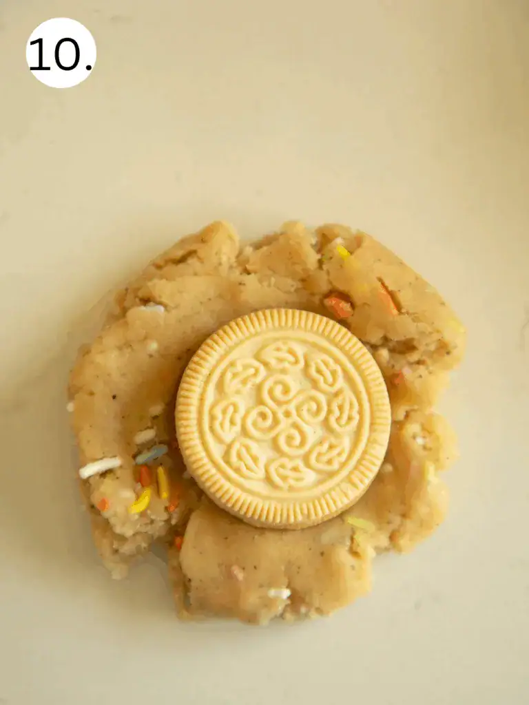 Golden Oreo placed on top of funfetti cookie dough disk for stuffing