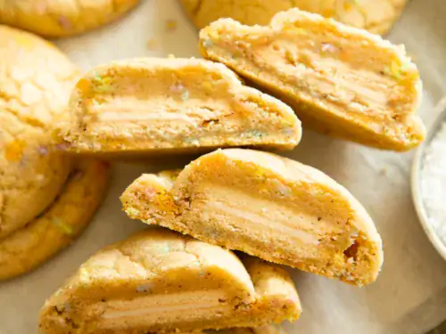 Brown butter funfetti cookies broken in half to reveal Golden Oreo filling inside