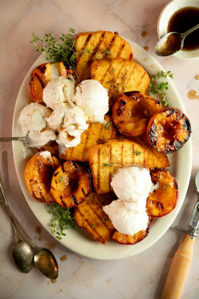 Overhead shot of grilled peaches and pound cake with melted vanilla ice cream on top.