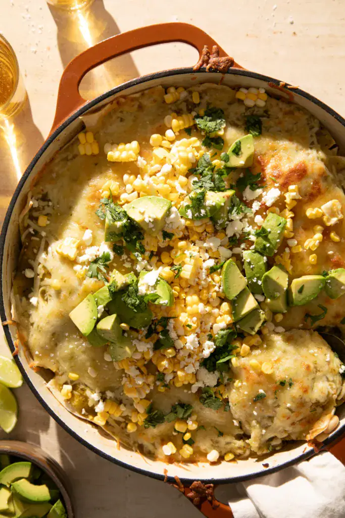 Final styled overhead shot of green chile turkey enchilada skillet topped with sweet corn, avocado, cotija, and cilantro.
