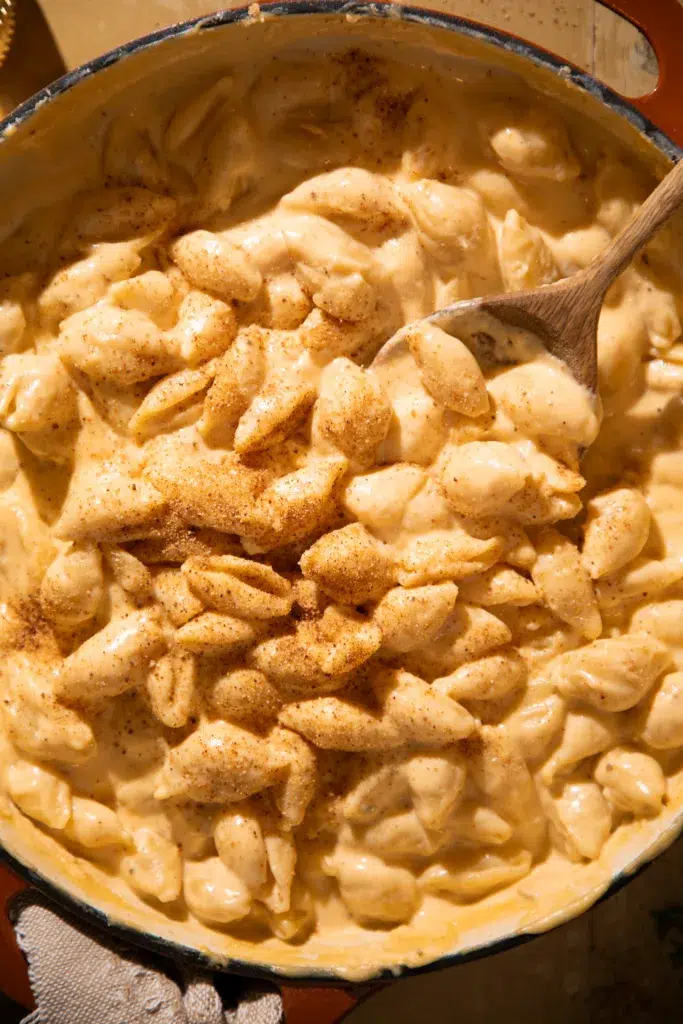 Overhead of creamy pasta shells topped with a dusting of paprika in a large pot.