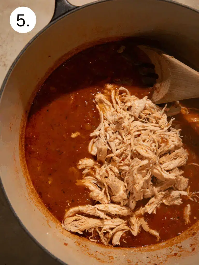 Tender shredded chicken stirred back into the simmered tomato and spice broth.
