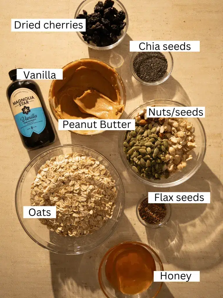 Ingredients for no-bake breakfast cookies including oats, peanut butter, honey, dried cherries, nuts, seeds, chia seeds, flax seeds, and vanilla