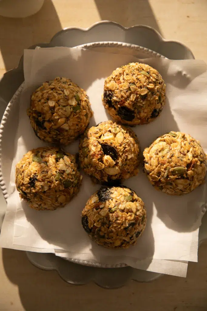 Stack of chewy no-bake breakfast cookies with oats, nuts, seeds, and dried cherries on parchment paper.