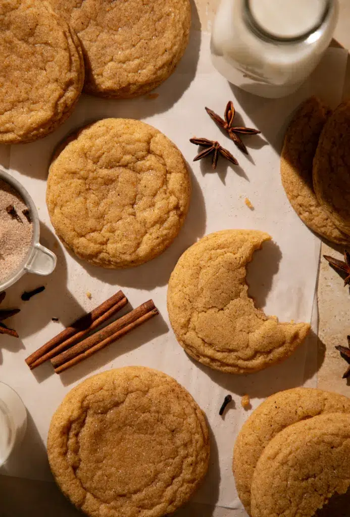 Soft pumpkin chai snickerdoodles on parchment with cinnamon sticks and star anise.
