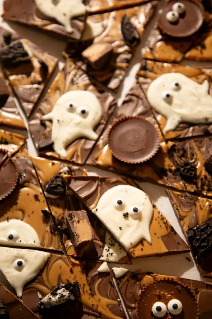 Halloween chocolate bark broken into pieces with spooky ghost decorations and Reese’s candy.