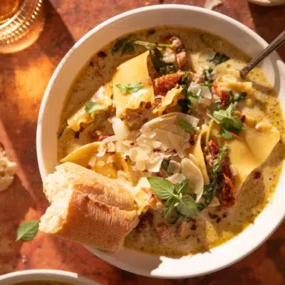 Hearty bowl of white lasagna soup with lasagna noodles, turkey, and parmesan, served with crusty bread.
