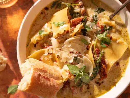 Hearty bowl of white lasagna soup with lasagna noodles, turkey, and parmesan, served with crusty bread.