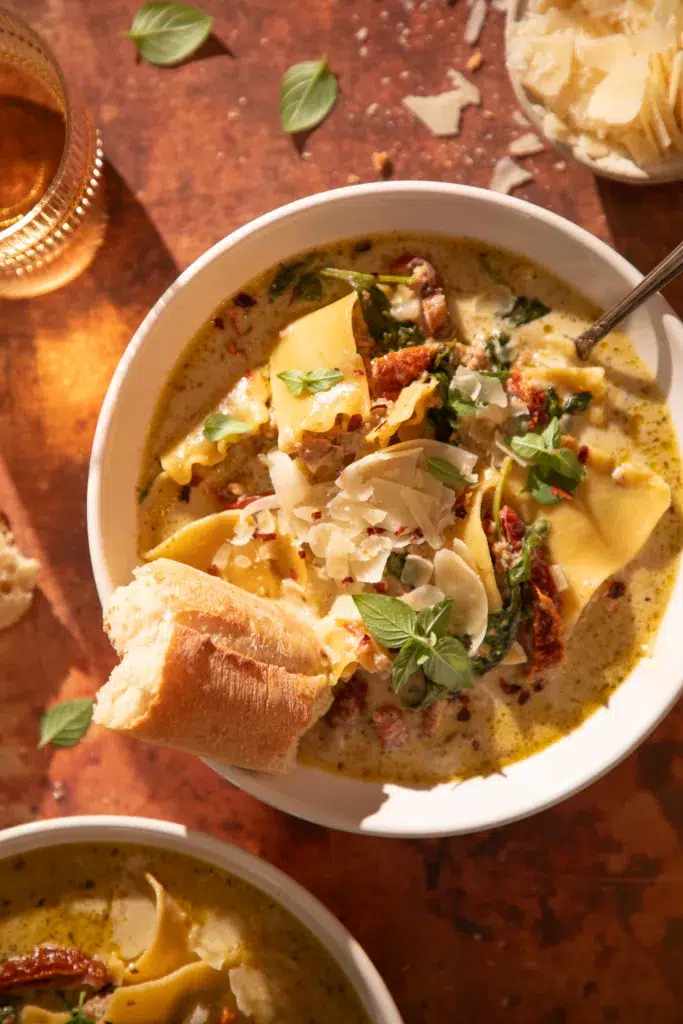 Hearty bowl of white lasagna soup with lasagna noodles, turkey, and parmesan, served with crusty bread.