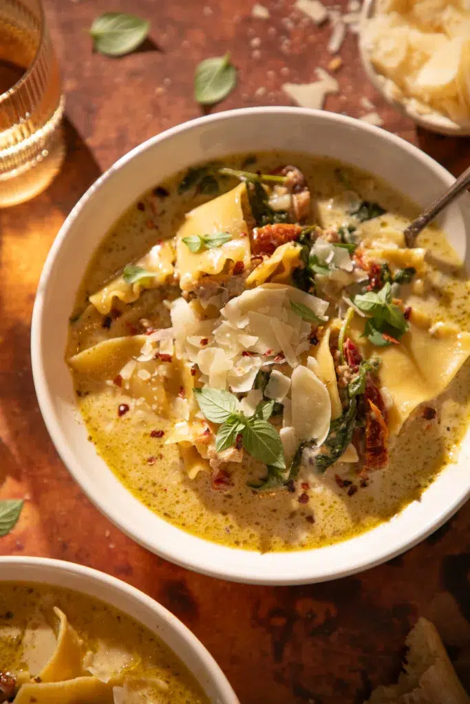 White lasagna soup garnished with fresh basil and shaved parmesan.