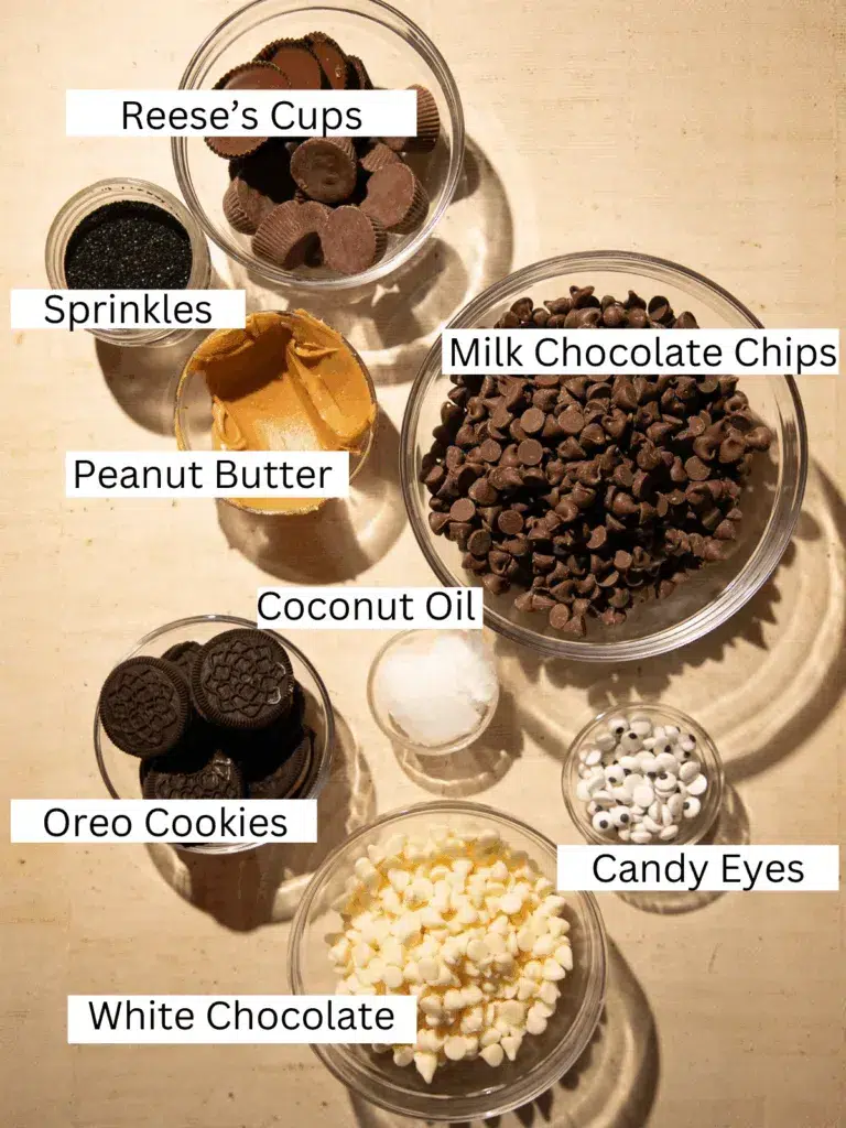 Ingredients for Halloween Peanut Butter Chocolate Ghost Bark including milk chocolate chips, peanut butter, Reese’s Cups, Oreo cookies, white chocolate, candy eyes, coconut oil, and sprinkles.