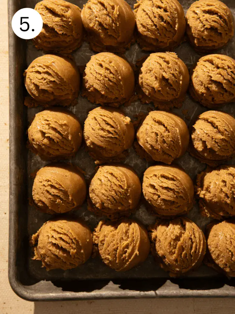 Cookie dough balls rolled in white sanding sugar and brown sugar before baking chewy ginger cookies.
