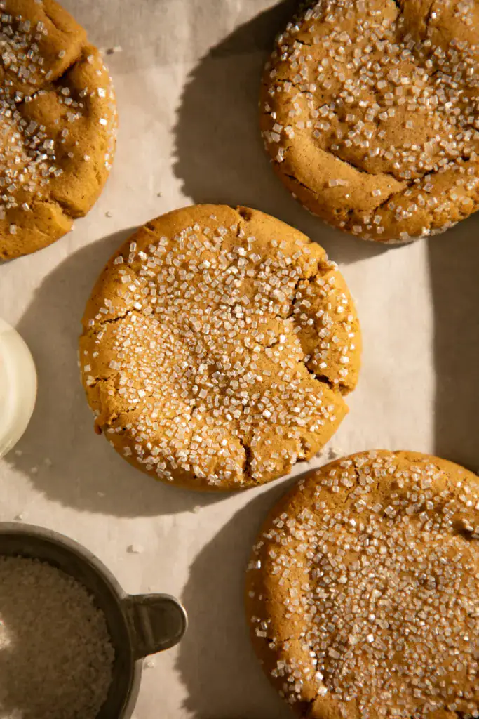 Freshly baked chewy ginger cookies sprinkled with sanding sugar and served with a glass of milk.