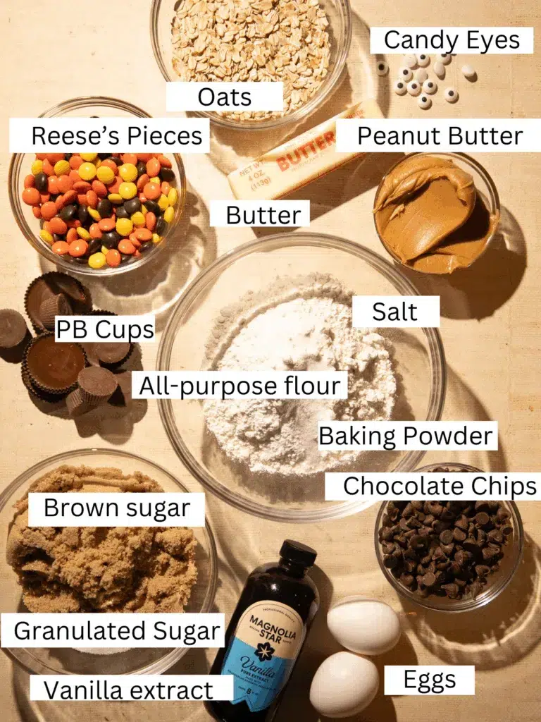 Ingredients for Halloween Reese’s Monster Cookie Bars including oats, peanut butter, Reese’s Pieces, Reese’s Cups, chocolate chips, candy eyes, flour, sugar, butter, eggs, and vanilla