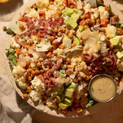 Overhead photo of roasted cauliflower salad topped with parmesan and drizzled lemon tahini dressing.