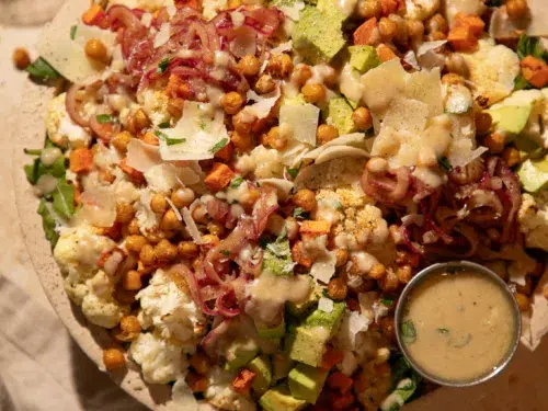 Overhead photo of roasted cauliflower salad topped with parmesan and drizzled lemon tahini dressing.