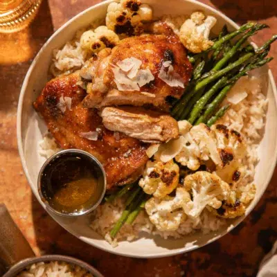 Juicy roasted chicken thighs served over rice with asparagus and roasted cauliflower, topped with parmesan shavings.
