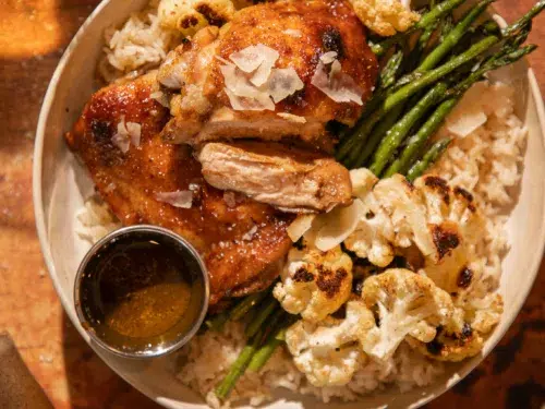 Juicy roasted chicken thighs served over rice with asparagus and roasted cauliflower, topped with parmesan shavings.