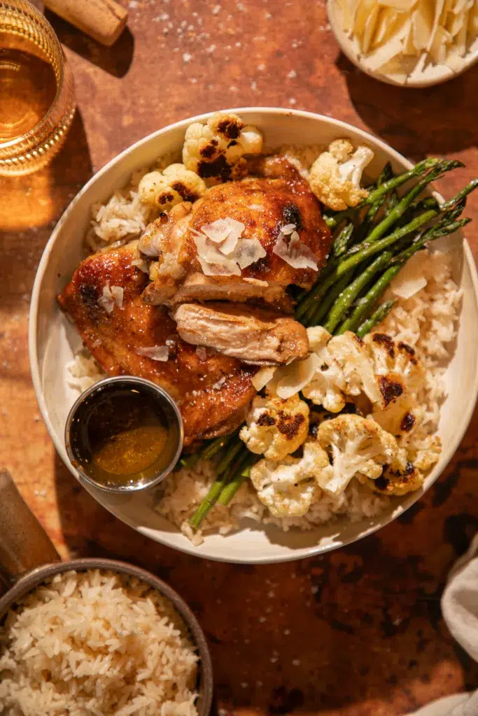 Juicy roasted chicken thighs served over rice with asparagus and roasted cauliflower, topped with parmesan shavings.