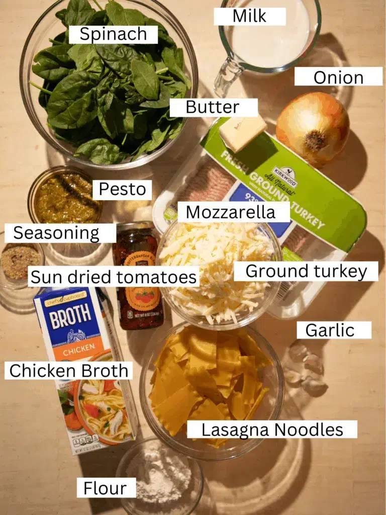 Ingredients for slow cooker white lasagna soup including ground turkey, spinach, sun-dried tomatoes, pesto, mozzarella, chicken broth, and lasagna noodles.