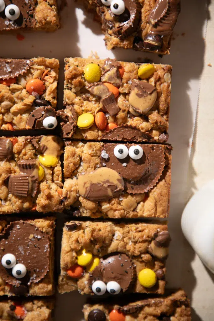 Baked Halloween Monster Cookie Bars loaded with Reese’s candy and decorated with candy eyes for a spooky effect.