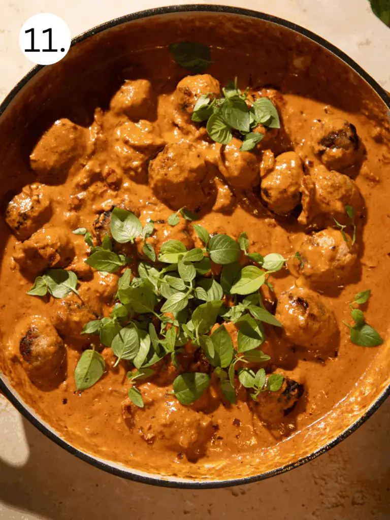 Juicy chicken meatballs simmered in creamy sun-dried tomato marry me sauce, topped with fresh basil leaves.