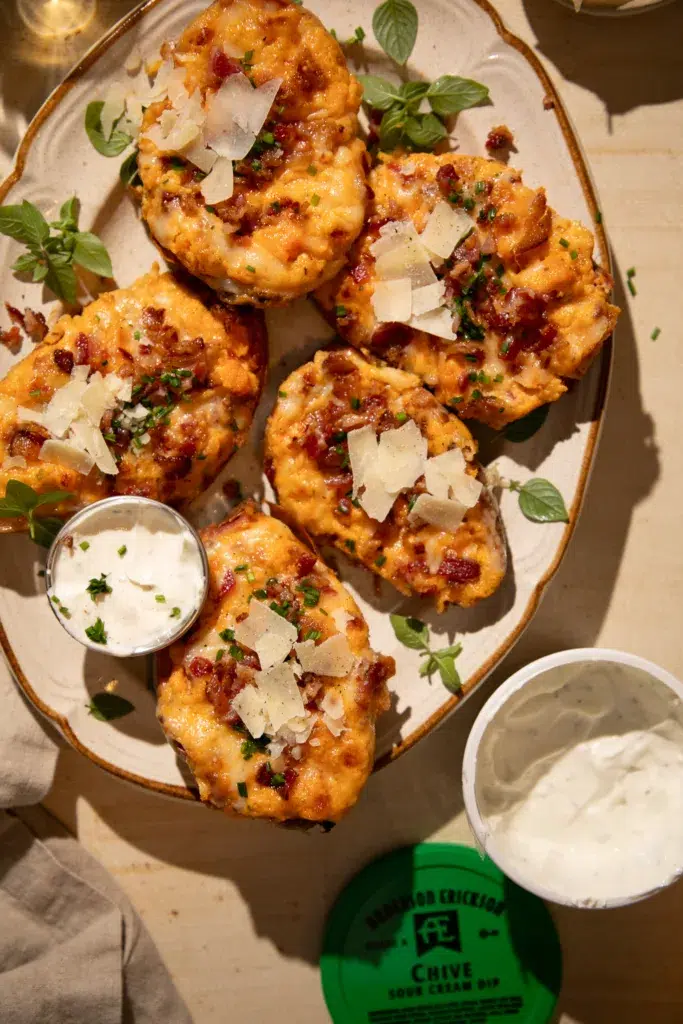 Platter of twice baked sweet potatoes topped with cheddar, bacon, and chives, served with sour cream dip.