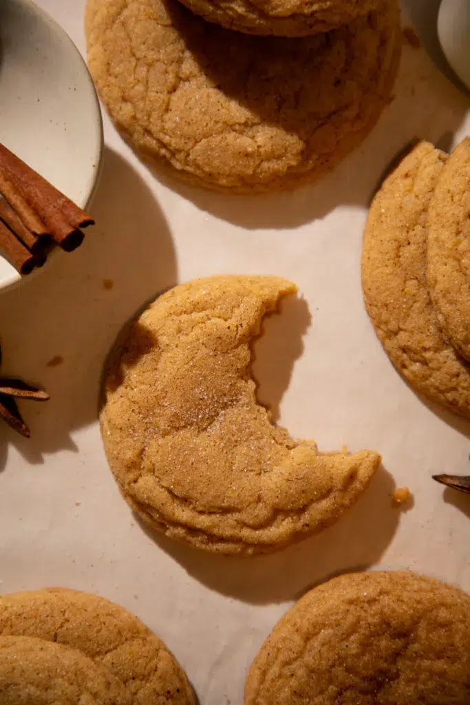 Soft pumpkin chai snickerdoodle cookie with a bite taken out, showing chewy center.