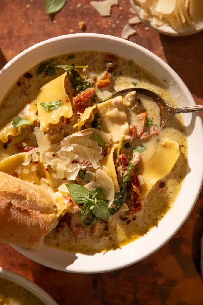 White lasagna soup with turkey, spinach, and sun-dried tomatoes served with bread for dipping.