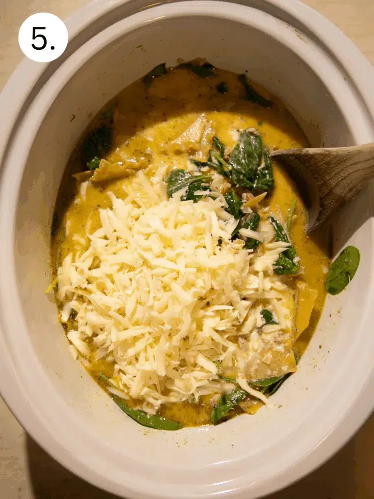 Shredded mozzarella cheese melting into creamy white lasagna soup.