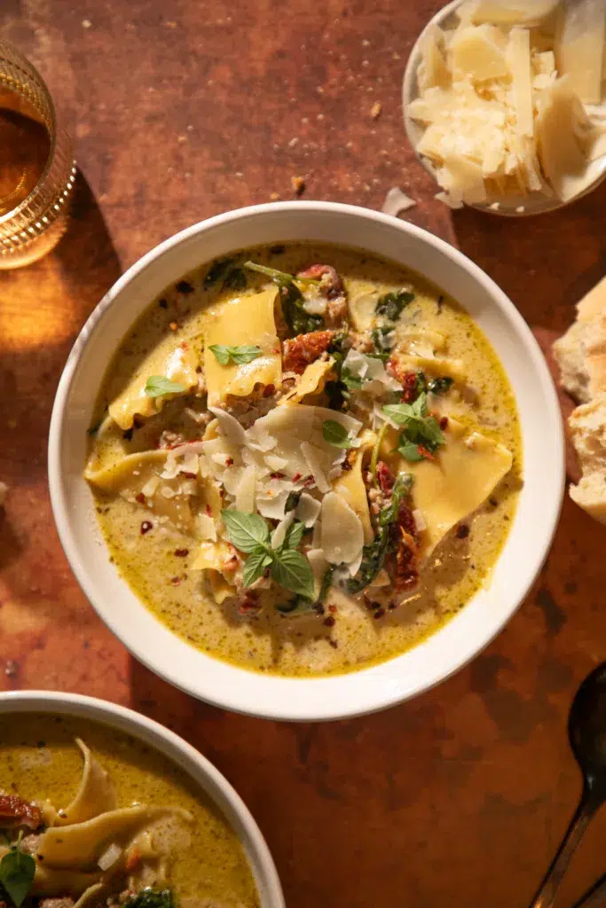 Bowl of creamy slow cooker white lasagna soup with turkey, spinach, sun-dried tomatoes, and parmesan.